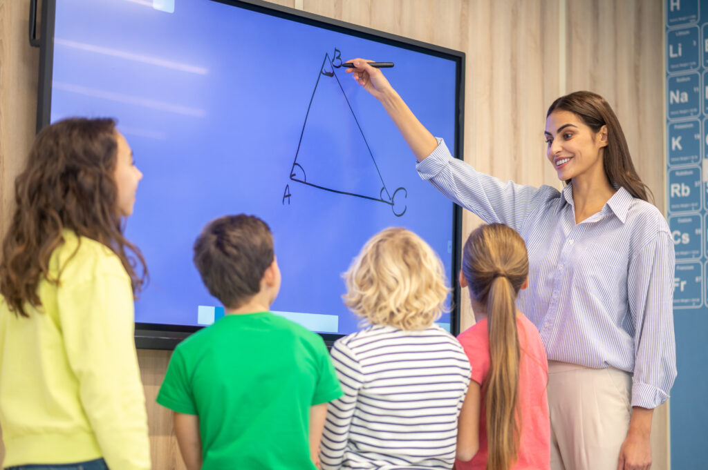 TBI, TNI, ENI : quelle différence entre tableau blanc interactif et écran interactif ? 4 Enseignante utilisant un écran interactif avec ses élèves
